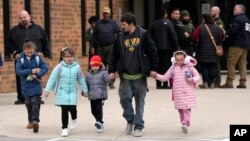 A man and children leave the McCreary Community Building after being reunited following a shooting at Perry High School, Jan. 4, 2024, in Perry, Iowa.