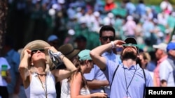 Patrons use special protective glasses to observe a total solar eclipse during a practice round at The Masters, at Augusta National Golf Club, Augusta, Georgia, April 8, 2024.