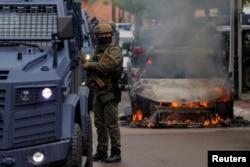 A special police forces officer stands next to a burning car, following clashes between Kosovo police and ethnic Serb protesters, who tried to prevent a newly-elected ethnic Albanian mayor from entering his office, in the town of Zvecan, Kosovo.