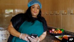 Anita Akpeere, who uses her mobile phone to run her business, stands inside her restaurant in Accra, Ghana, April 23, 2024.