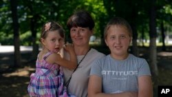 FILE - Kateryna Krupych holds her daughter, Masha, 4, as she posses for a photograph next to her son, Maksim, in Kherson, Ukraine, June 13, 2023.