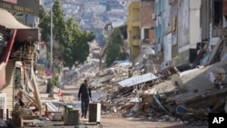 FILE - A man walks past destroyed buildings in Antakya, southeastern Turkey, Feb. 21, 2023, two weeks after a powerful earthquake struck Turkey and Syria.