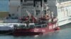 This image from video shows a ship belonging to Spanish aid group Open Arms, background, and a barge docked at Larnaca port in Cyprus, March 11, 2024. World Central Kitchen posted on X that the ship, loaded with some 200 tons of food, set sail on March 12.