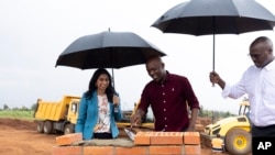 British Home Secretary Suella Braverman, left, and Rwanda's Minister of Infrastructure Ernest Nsabimana, center, lay bricks in Kigali, Rwanda, March 19, 2023.