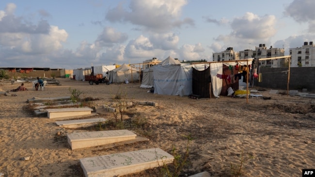 Displaced Palestinians from the eastern part of Khan Yunis set up a temporary camp in the grounds of a cemetery in the western part of the city, in the southern Gaza Strip, on July 26, 2024.