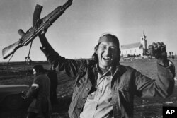 FILE - A man holds up a rifle in Wounded Knee, South Dakota, in Feb. 1973. On Feb. 27, 1973, members of the American Indian Movement took over the town, starting a 71-day occupation on the Pine Ridge Indian Reservation.
