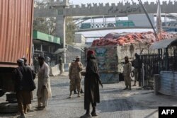 Petugas keamanan berjaga saat truk melewati titik nol perbatasan Torkham antara Afghanistan dan Pakistan, di provinsi Nangarhar pada 23 Januari 2024. (Syafiullah KAKAR/AFP)