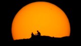 Hikers are silhouetted against the setting sun at Papago park, Feb. 18, 2023, in Phoenix, Arizona. 