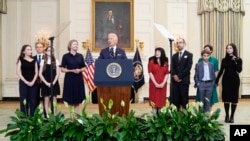 President Joe Biden, center, delivers remarks on a prisoner exchange with Russia, at the State Dining Room of the White House in Washington, Aug. 1, 2024, as family members of some of those swapped look on.