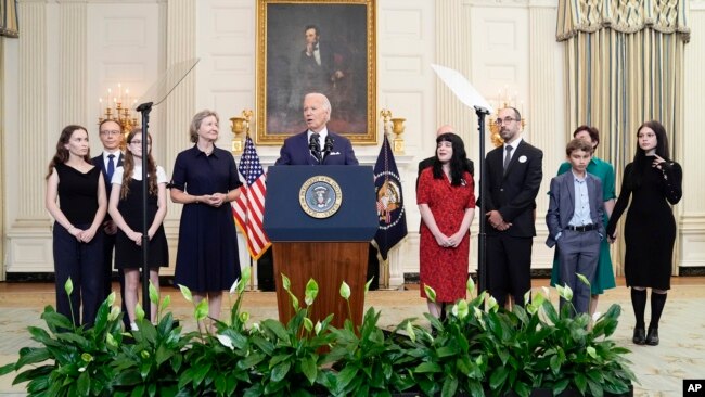 President Joe Biden, center, delivers remarks on a prisoner exchange with Russia, at the State Dining Room of the White House in Washington, Aug. 1, 2024, as family members of some of those swapped look on.