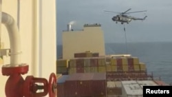 In this photo taken from video, an Iranian commando rappels from a helicopter in a raid on the MSC Aries in the Strait of Hormuz on April 13, 2024.