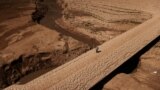 A man walks on the cracked ground of the Baells reservoir as drinking water supplies have plunged to their lowest level due to extreme drought in Catalonia, in the village of Cersc, in the region Bergueda, Spain, March 14, 2023. 