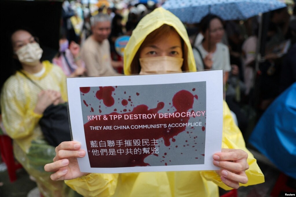 台湾民众聚集在台北的立法院外，一名女子手举表达自己政治意愿的标语牌。(2024年5月24日)(photo:VOA)