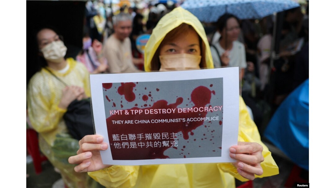 台湾民众聚集在台北的立法院外，一名女子手举表达自己政治意愿的标语牌。(2024年5月24日)