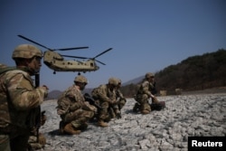 US soldiers withstand strong wind as a US Army CH-47 Chinook prepare to land during a military exercise which is a part of Freedom Shield joint military exercise at a training field near the demilitarized zone, in Pocheon, South Korea, March 19, 2023.