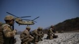 Солдаты США противостоят сильному ветру, когда вертолет CH-47 Chinook готовится к посадке во время совместных военных учений Freedom Shield на полигоне недалеко от демилитаризованной зоны, в Почхоне, Южная Корея. 19 марта 2023 г..