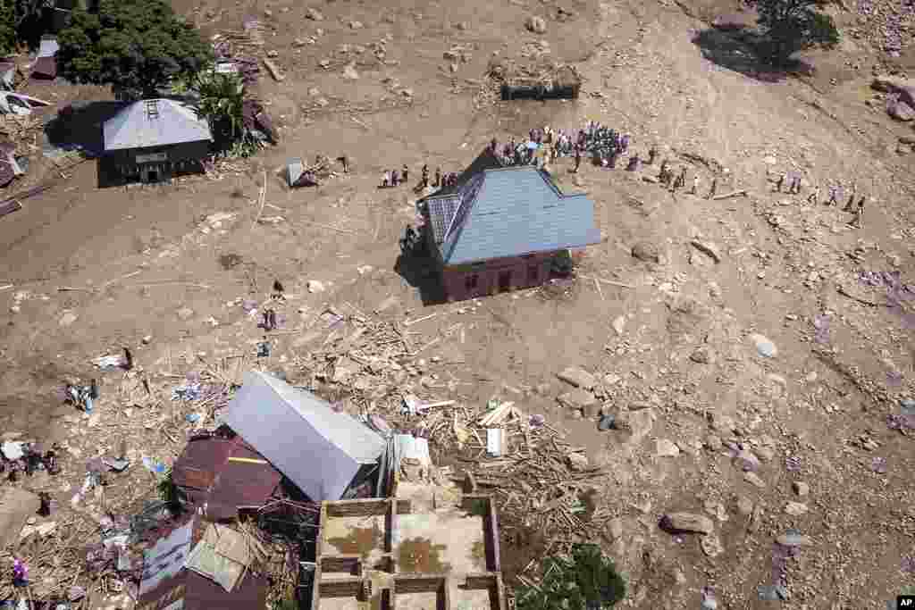 Survivors walk amidst debris next to destroyed buildings in the aftermath of floods in the village of Nyamukubi, South Kivu province, in the Democratic Republic of Congo Monday, May 8, 2023. The death toll from floods in eastern Congo climbed to several hundred people as of Sunday, according to a local official.&nbsp;