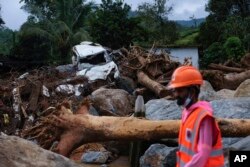 A rescuer walks past uprooted trees, a damaged car and other debris on their second day of mission following landslides at Chooralmala, Wayanad district, Kerala state, India, July 31, 2024.