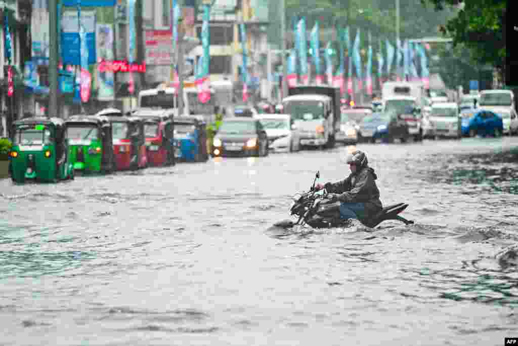 A man rides a motorbike through a flooded street after heavy rains in Colombo.