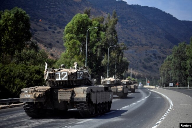 Un convoy de vehículos militares israelíes viaja por una carretera cerca de la frontera de Israel con el Líbano en el norte de Israel, el 8 de octubre de 2023.