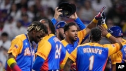 Anthony Santander (centro) es felicitado por sus compañeros de Venezuela tras batear un jonrón ante República Dominicana, en un duelo del Clásico Mundial, realizado el sábado 11 de marzo de 2023, en Miami (AP Foto/Wilfredo Lee)