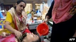 বাংলাদেশের রাজধানী ঢাকার মুগদা মেডিকেল কলেজ ও হাসপাতালে জ্বর কমানোর জন্য এক ডেঙ্গু রোগীর কপালে পানি ঢালছেন তার এক স্বজন। (ফাইল ছবি) 