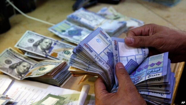 FILE - A man counts Lebanese pounds at an exchange shop, in Beirut, Lebanon, Aug. 20, 2018. Lebanon's embattled currency hit a new low March 14, 2023.