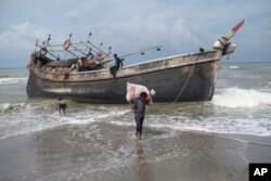 Etnis Rohingya mengumpulkan barang-barang dari perahu mereka setelah mendarat di Pantai Lampanah Leungah di Aceh Besar, Kamis, 16 Februari 2023. (Foto: AP)