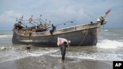 Pengungsi Rohingya mengumpulkan barang-barang dari kapal mereka setelah mendarat di pantai Lampanah Leungah di Aceh Besar, provinsi Aceh, Kamis, 16 Februari 2023. (AP/Riska Munawarah)