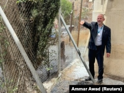 Direktur urusan UNRWA di Tepi Barat Adam Bouloukos menunjukkan dampak kebakaran di dekat markas UNRWA, di Yerusalem, 10 Mei 2024. (Foto: REUTERS Sinan Abu Mayzer)