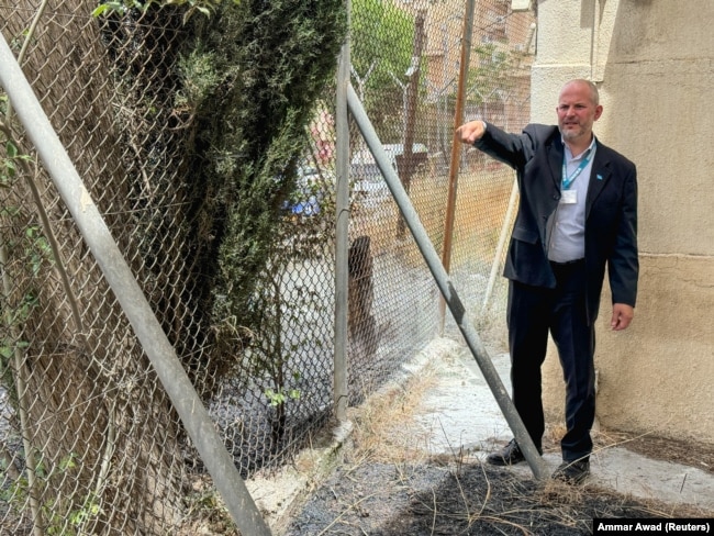 Direktur urusan UNRWA di Tepi Barat Adam Bouloukos menunjukkan dampak kebakaran di dekat markas UNRWA, di Yerusalem, 10 Mei 2024. (Foto: REUTERS Sinan Abu Mayzer)