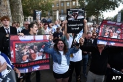 民众手举被巴勒斯坦武装分子劫为人质的以色列妇女和儿童的照片在伦敦的英国首相官邸唐宁街10号外举行支持以色列的集会。（2023年10月9日）