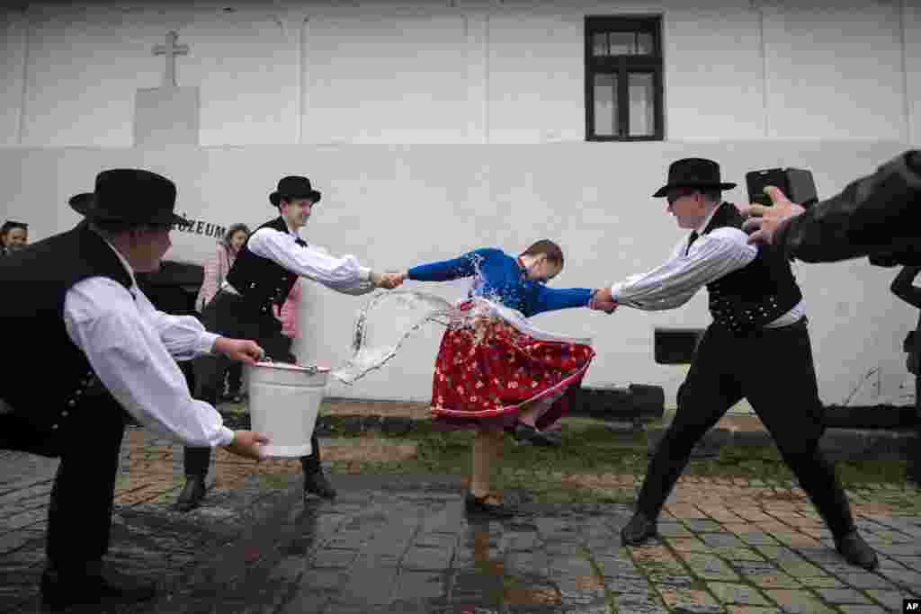 Hungarian men wearing folk clothing pour water onto women during a traditional Easter Monday celebration in Holloko.