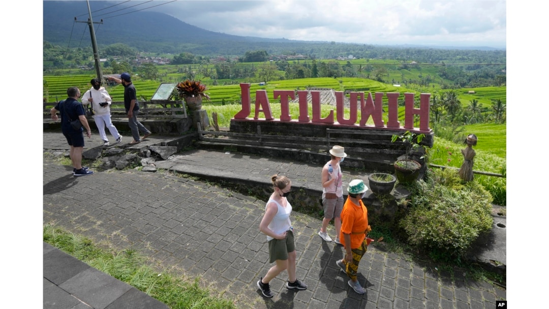 Turis berjalan di dekat sawah yang diairi oleh sistem terasering tradisional yang disebut "subak" di Jatiluwih di Tabanan, Bali, Senin, 18 April 2022. (AP/Tatan Syuflana)