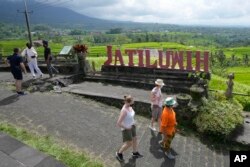 Turis berjalan di dekat sawah yang diairi oleh sistem terasering tradisional yang disebut "subak" di Jatiluwih di Tabanan, Bali, Senin, 18 April 2022. (AP/Tatan Syuflana)