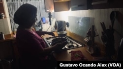  Una venezolana, de 71 años, cocina la cena de su familia durante un apagón en Maracaibo, estado Zulia, la noche del 23 de mayo de 2023, mientras la alumbra una lámpara de emergencia.