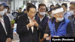 日本首相岸田文雄在东京一个水产品市场时食用福岛附近水域打捞的海鲜。（2023年8月31日）