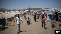 FILE - People walk along the main road of Kumer refugee camp, near Maganan, 70 km from the Sudanese border in Ethiopia's Amhara region, on Feb. 29, 2024.