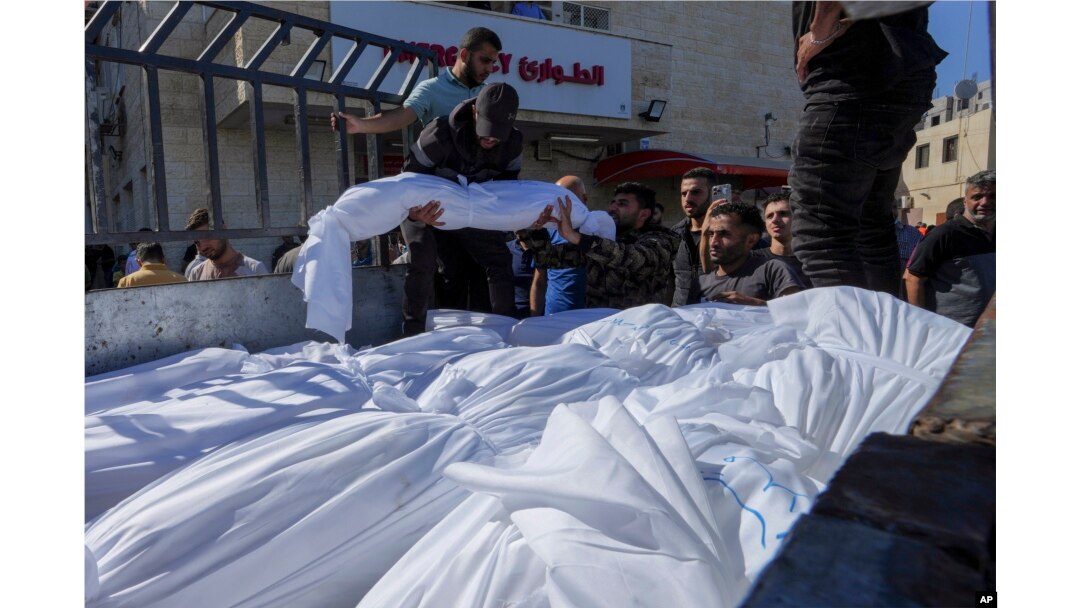 Sheet-covered bodies killed during an Israeli airstrike are loaded onto a truck outside al-Aqsa hospital in Deir el-Balah, central Gaza Strip, Oct. 15, 2023.