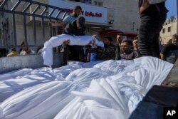 Sheet-covered bodies killed during an Israeli airstrike are loaded onto a truck outside al-Aqsa hospital in Deir el-Balah, central Gaza Strip, Oct. 15, 2023.