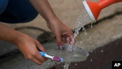 FILE - Abigail Lopez, a member of cooperative Pixcatl, cleans a filter from a water collector system at a community garden in Mexico City, July 14, 2024.