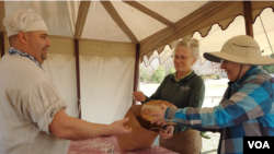 Leslie Bird, center, Mount Vernon’s historic gardens and landscape manager, buys a loaf of bread from Justin Cherry. She said she is gluten-intolerant but thinks she can eat Cherry’s bread because it is made from heritage grains. (Deborah Block/VOA)