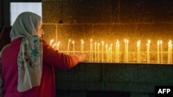 A woman lights candles during the Easter mass at the Armenian church Surp Giragos, in Diyarbakir, southeastern Turkey, on April 9, 2023. 