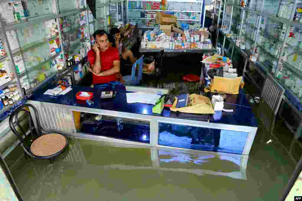 Shopkeepers attend a phone call as they wait for customers at a medical store in Fenchuganj, in Sylhet, Bangladesh.