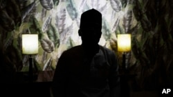 FILE - An atheist sits in a dimly lit room during an interview in Kano, Nigeria, July 14, 2023.