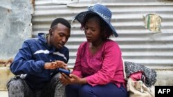 FILE - Roseline Asena (R) and her son Lewis Kodack look at photos of their relatives, believed to be victims of the so-called "Shakahola forest massacre," on May 2, 2023. -