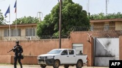 Seorang anggota kepolisian nasional Niger berjaga di depan Kedutaan Besar Prancis di Niamey, Niger, pada 28 Agustus 2023. (Foto: AFP)