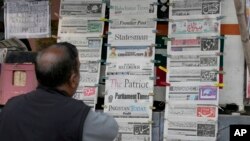 A man checks morning newspapers covering front page story of Iran's strike, at a stall in Islamabad, Jan. 18, 2024. 
