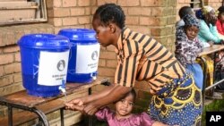 A child has her hands washed at a displacement center in Blantyre, southern Malawi March 16, 2023. 