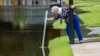 A resident measures the depth of stormwater in a flooded street in Pooler, Georgia, Aug. 7, 2024. 